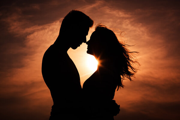 Пара влюбленных силуэт во время заката - прикосновения носов
