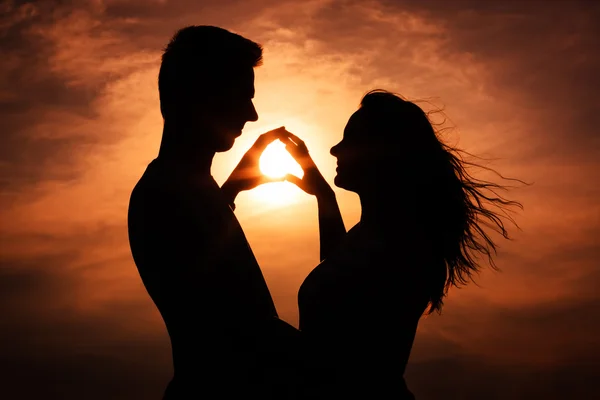 Pareja en la silueta del amor durante la puesta del sol - tocar las manos —  Fotos de Stock
