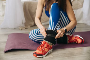 Spor hazırlıkları, bacaklarda ağırlık. Spor kızı evde yoga yapıyor.