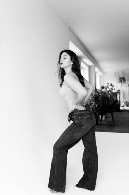 Stüdyoda genç bir kız üstte ve pantolonla poz veriyor.
