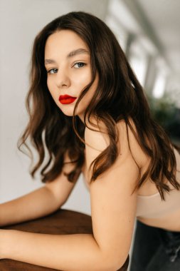 Stüdyoda beyaz arka planda bar taburesiyle fotoğraf için poz veren genç seksi manken.