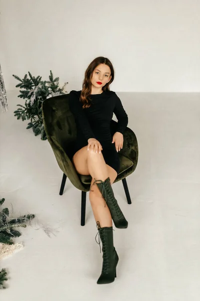 하얀 스튜디오 의자에 앉아 있는 검은 옷을 입은 모델 — 스톡 사진