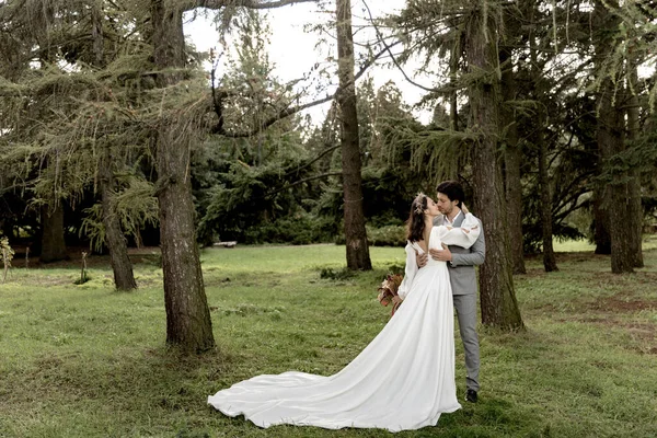 Casal bonito de recém-casados abraçando e beijando em uma floresta de coníferas — Fotografia de Stock