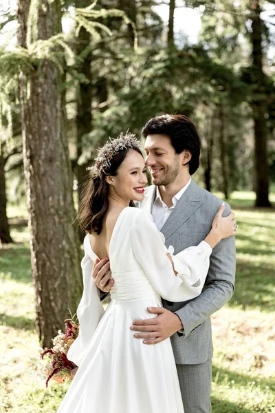 Happy newlywed couple smiling and hugging in the forest — стоковое фото