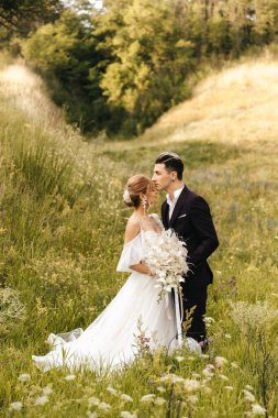 Düğün çifti yeni evliler, tepelerin arkasında şefkatle sarılıp öpüşürler. Yüksek kalite fotoğraf