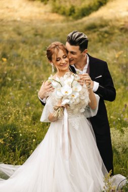 Doğada kucaklaşan güzel yeni evliler. Tepelerin arka planında şık bir çift. Yüksek kalite fotoğraf