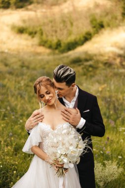 Doğada kucaklaşan güzel yeni evliler. Tepelerin arka planında şık bir çift. Yüksek kalite fotoğraf