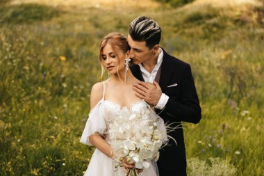 Doğada kucaklaşan güzel yeni evliler. Tepelerin arka planında şık bir çift. Yüksek kalite fotoğraf