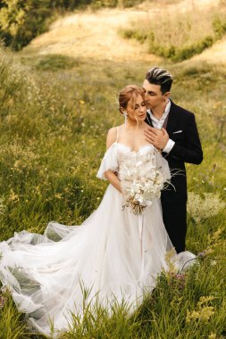 Doğada kucaklaşan güzel yeni evliler. Tepelerin arka planında şık bir çift. Yüksek kalite fotoğraf