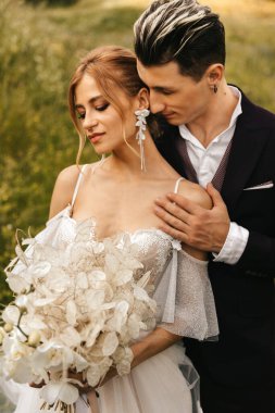 Yeni evli çiftimiz doğanın arka planında sevgiyle sarılıyorlar. Yüksek kalite fotoğraf