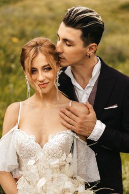 Yeni evli çiftimiz doğanın arka planında sevgiyle sarılıyorlar. Yüksek kalite fotoğraf