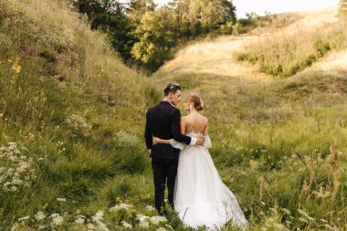 Doğanın arka planında sarılan şık bir çift yeni evli. Yüksek kalite fotoğraf