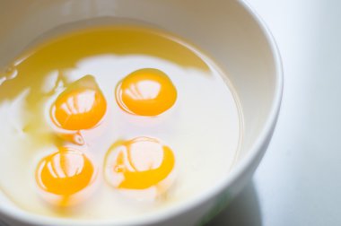 Beyaz bir kase içinde dört sarı yumurta sarısı.