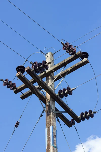 Poste eléctrico por la carretera con cables de línea eléctrica, contra azul — Foto de Stock