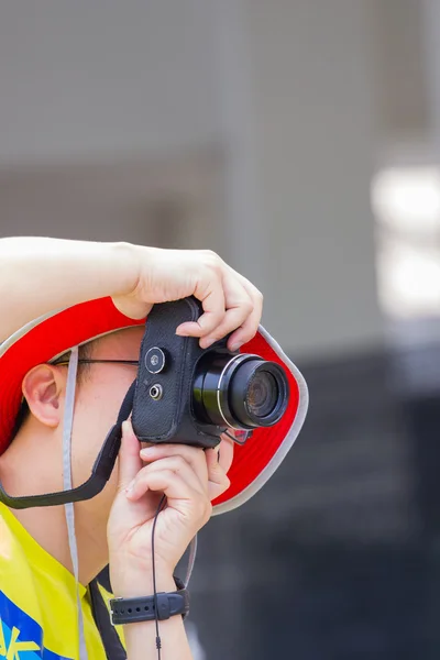 Homem com chapéu vermelho tirando uma foto com câmera preta — Fotografia de Stock