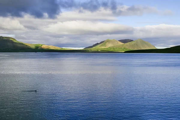 's avonds IJslandse lake tegen heuvels en bewolkte hemelachtergrond — Stockfoto