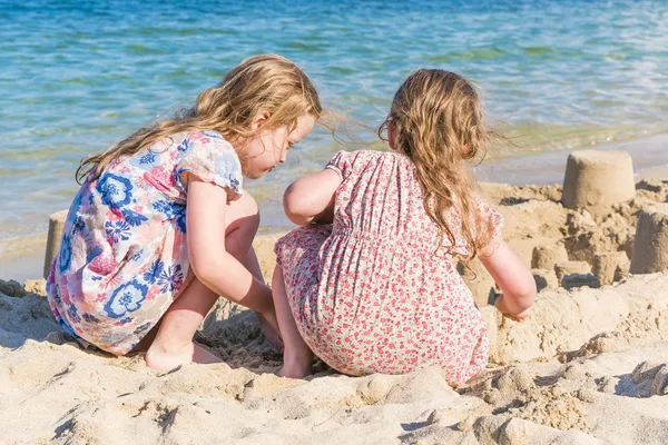 Deux petites filles jouant avec le sable sur le bord de la mer — Photo