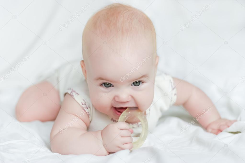 Baby girl on her stomach with teether in the mouth