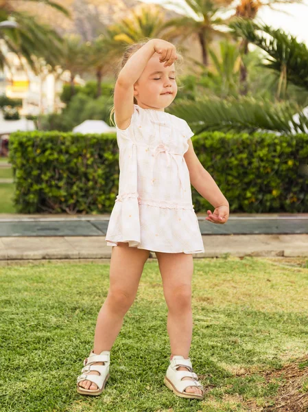 Petite fille dansant sur la pelouse les yeux fermés contre le parc ba — Photo