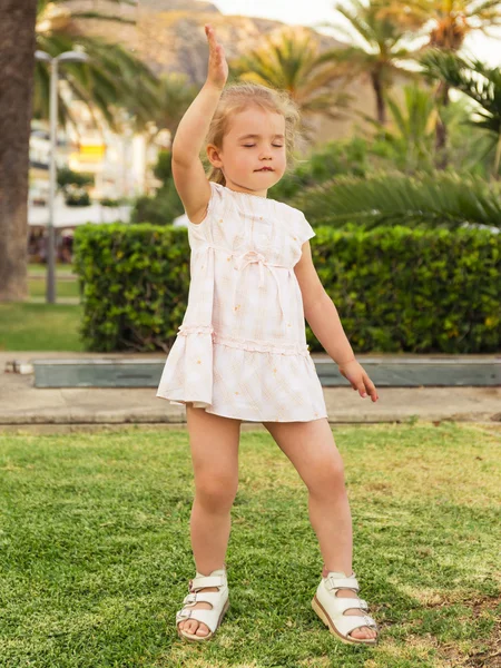Petite fille dansant sur la pelouse les yeux fermés contre le parc ba — Photo