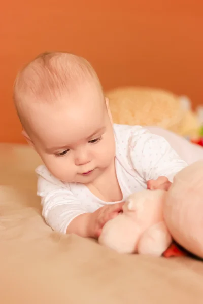 Meisje van de baby liggend op haar maag en spelen met een stuk speelgoed — Stockfoto