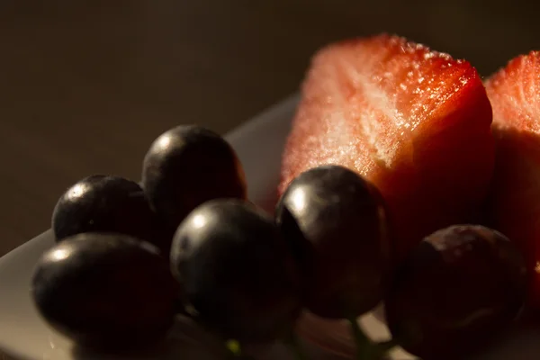 Morangos fatiados com uvas de videira — Fotografia de Stock