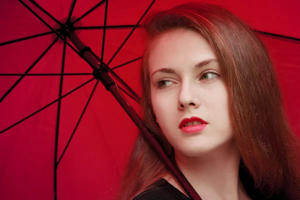 Kırmızı şemsiye altında duran kırmızı dudaklar ile kız — Stok fotoğraf
