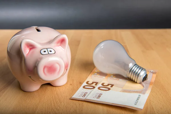 Konzept Energiepreis Sparschwein Mit Glühbirne Und Geld Auf Holzgrund — Stockfoto