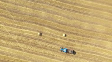 Çiftçi tarlasında saman rulosu yapıyor.