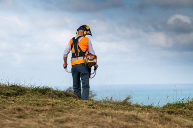 Elektrikli fırça makası kullanarak çayırı biçiyorum.
