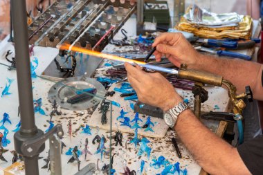 Glassmaker making glass objects in his workshop