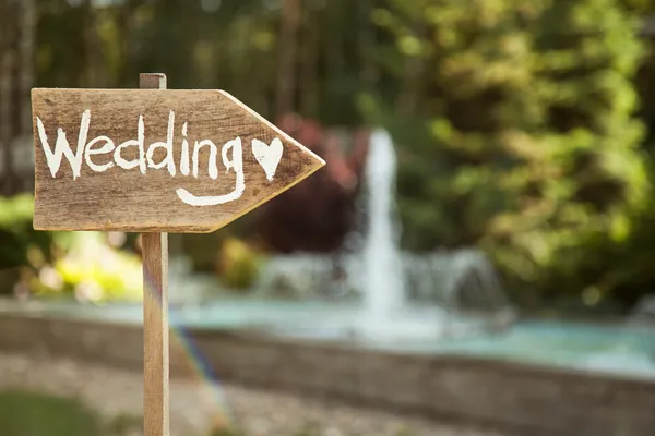 Wedding decor. Wooden plaque with the inscription Wedding. Wedding on a plate green background and a fountain. Wedding decorations are beautiful. Summer wedding celebration. — Stock Photo, Image