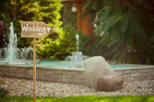 Düğün dekorasyonu. ahşap plaket yazıt düğün yüzünden. Düğün bir tabak yeşil arka plan ve bir çeşme. Düğün süslemeleri güzel. yaz düğün kutlama.