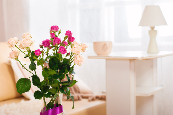 Bouquet of flowers in a room in the interior. Red and white rose in a vase on a table in a bright room.