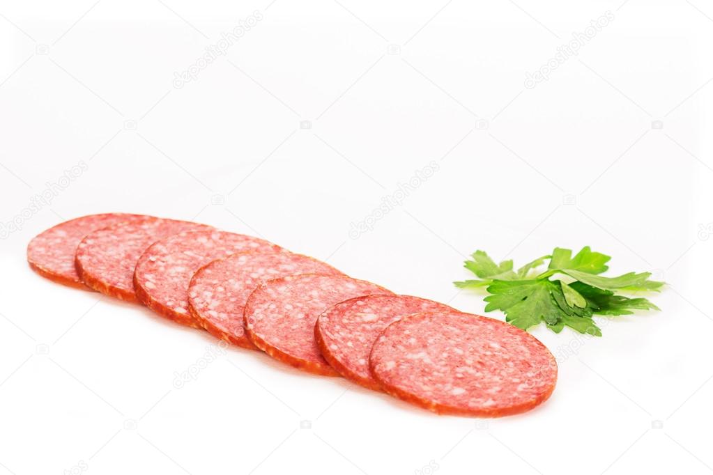 Salami sausage cut into thin slices on a white background