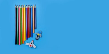 Renkli kalemler, bir roketin heykelcikleri ve mavi arka planda bir astronot. Çizim yapmayı öğreniyorum. Çalışmayla ilgili metin için pankart.