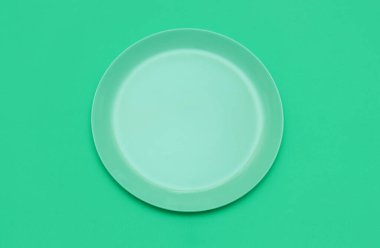 Yeşil arka planda yeşil yuvarlak boş bir tabak. Üst görünüm.