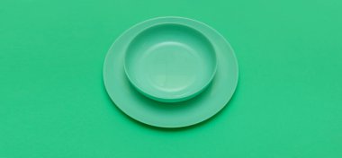 Yeşil arka planda tabağı olan yeşil yuvarlak boş tabak. Restoran ya da yeşil diyet hakkında metin ekleniyor.