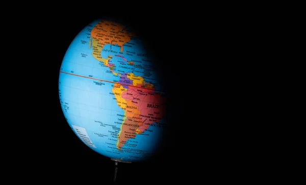 Globe planet earth with political map of the world on a dark background, illuminated countries of North and South America.