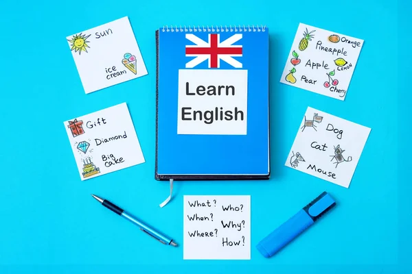 Notepad with text: Learn English stickers with words on a blue background. Top view.
