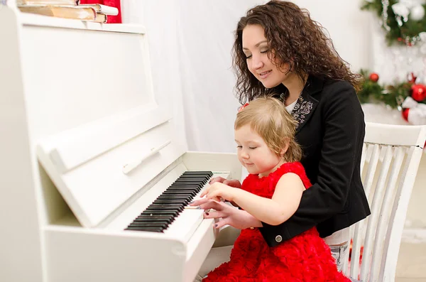 Moeder en dochter spelen op witte piano — Stockfoto