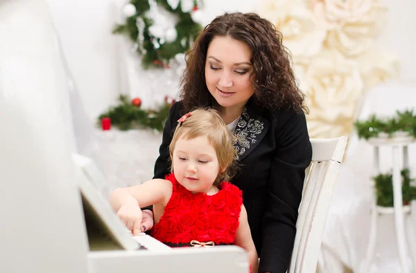 Mor och dotter spelar på vit piano — Stockfoto