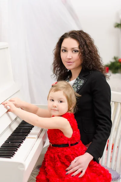 Mother and daughter playing on white piano — Stock Photo, Image