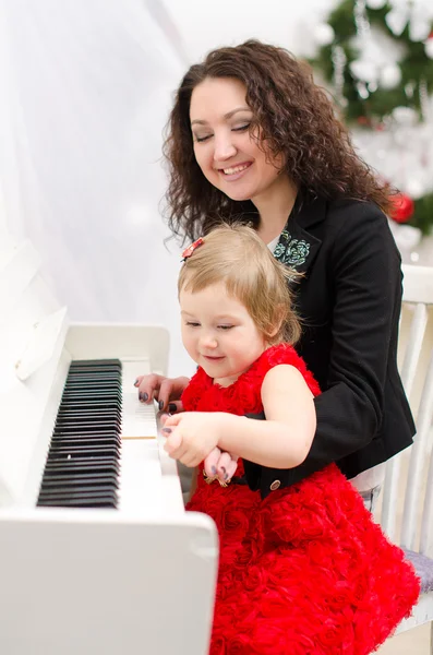 Mor och dotter spelar på vit piano — Stockfoto