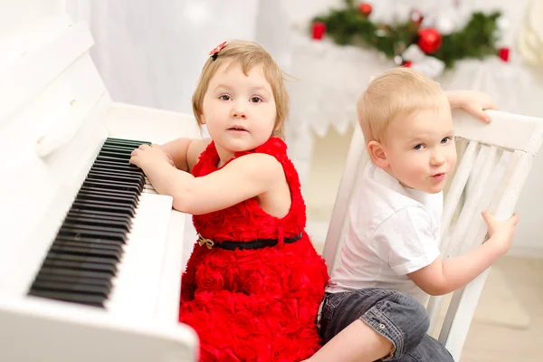 Pojke och flicka som leker på vit piano — Stockfoto