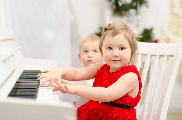 Boy and girl playing on white piano — Stock Photo, Image