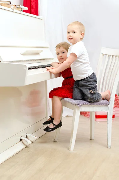 Jongen en meisje spelen op witte piano — Stockfoto