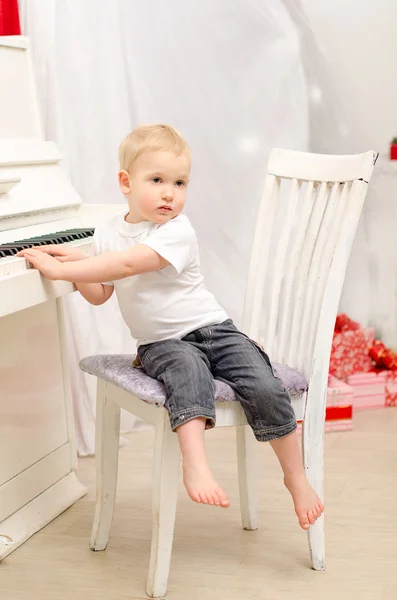 Jongen zitten in de buurt van witte piano — Stockfoto