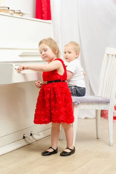 Chico con chica sentado cerca blanco piano — Foto de Stock