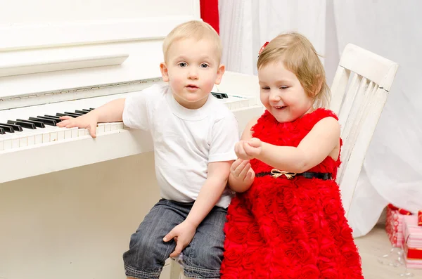 Chico con chica sentado cerca blanco piano —  Fotos de Stock